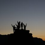 silhouette of five people standing on rocks