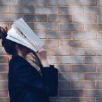 person with a book in her face